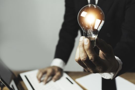 Business man holding a light bulb with coins money and copy space for accounting, ideas and creative concept.