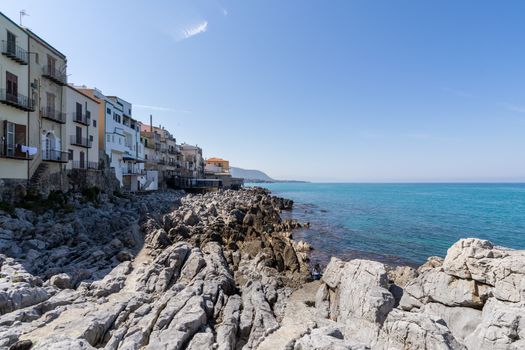 View over the coastline and residential buildings from Bastione di Capo Marchiafava bastion lookout point on a sunny day in Cefalu - Sicily, Italy.