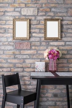 Two identical picture frame mockups hanging on the brick wall above the breakfast table.