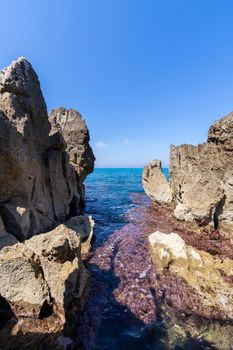 Idyllic view over the turquoise sea from the rocky coastline on a sunny day in Cefalu - Sicily, Italy.