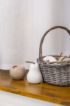 Still life - a basket of porcelain ceramic fruits in neutral colors on a window sill.