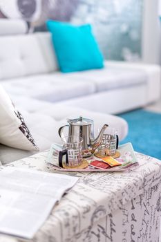 Teapot and cups setup on a tray in the living room, bright light mood - still life.