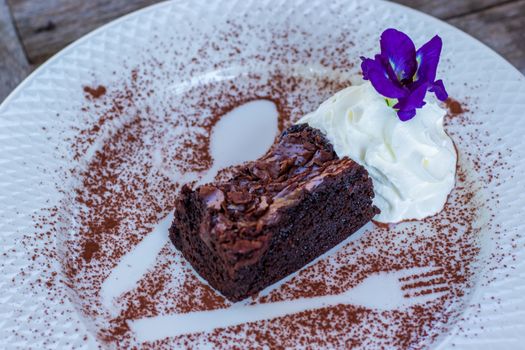 ิbrownie cake with chocolate and flowers on white dish