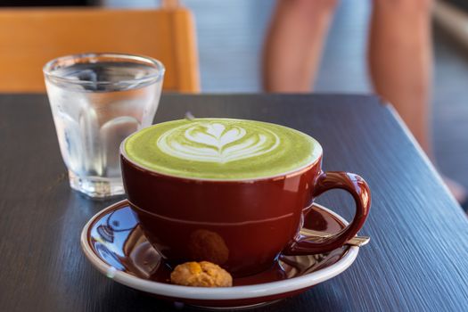 cup of hot matcha green tea latte on wooden table