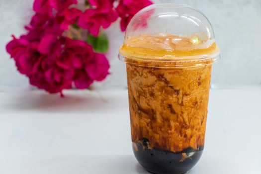 glass of Thai ice tea  and red flower on table