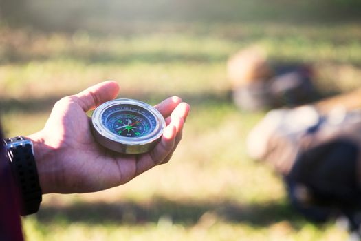 Hiker searching direction with a compass in the forest. View of hands. Point of view shot. Space for text in right left of image