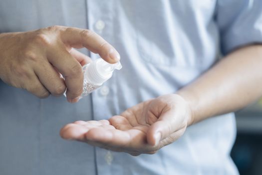 COVID-19, Close up man using bottle of antibacterial wash hand sanitizer gel dispenser, against Novel coronavirus (2019-nCoV) at home.  Home isolation and Healthcare concept.