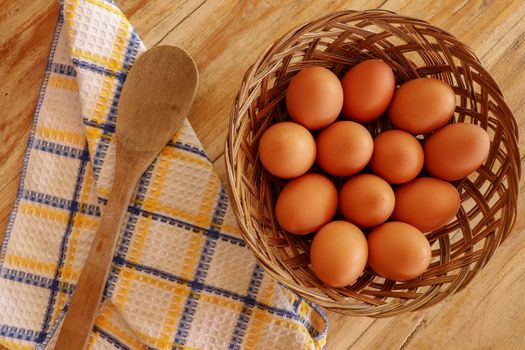 Top view of brown eggs in a wicker basket. Eggs in a wooden basket on a wooden table.