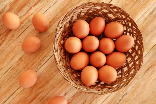 Top view of brown eggs in a wicker basket. Eggs in a wooden basket on a wooden table.