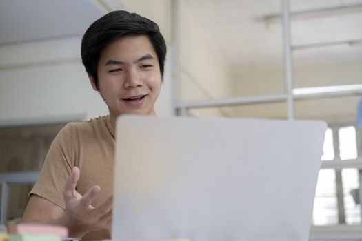 Online meeting and working at home or office. Happy young man speaking looking and using laptop for video conference. 