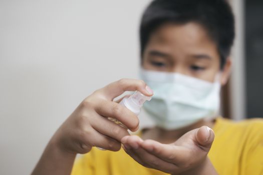 COVID-19, Close up boy using bottle of antibacterial wash hand sanitizer gel dispenser, against Novel coronavirus (2019-nCoV) at home.  Home isolation and Healthcare concept. 