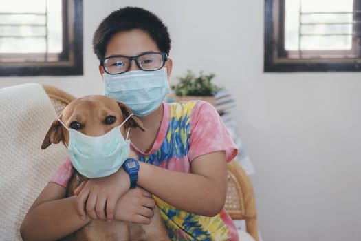 Boy in a medical mask puts a medical mask on his dog. Care for loved ones. Basic hygiene rules.