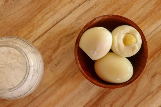 Boiled eggs with salt and herbs on a wooden table. Top view.