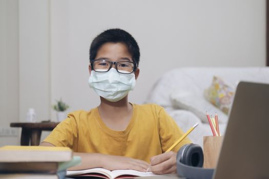 Boy wearing face masks online study homeshcooling at home.