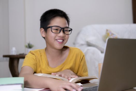 Cheerfully boy excited using computer online learning schoolwork. Asian boy enjoy self study with e-learning at home. Online education and self study and homeschooling concept.