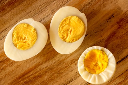 Hard boiled eggs, sliced in halves on wooden background.