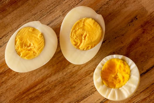 Hard boiled eggs, sliced in halves on wooden background.