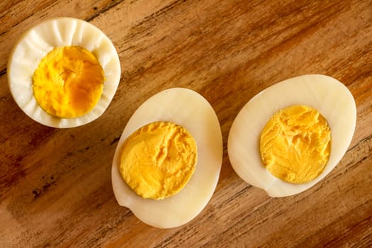 Hard boiled eggs, sliced in halves on wooden background.