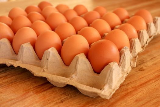 Brown fresh eggs in paper tray on white background,whole round raw brown homemade chicken eggs in a paper tray, selective focus, close up.Brown chicken in paper tray.