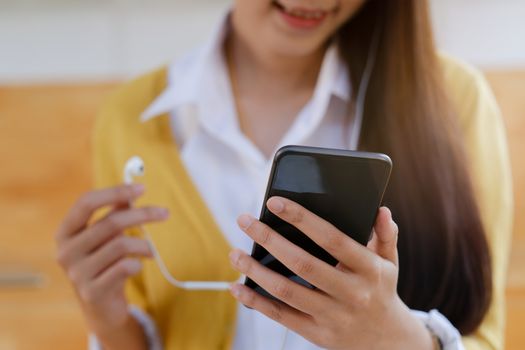 A young woman feel relaxed and listen to online music from mobile phone in her house.