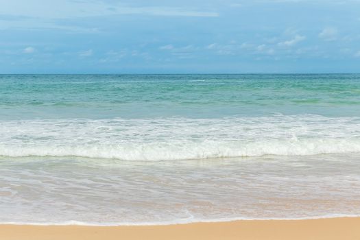 sandy beach blue sky and white formy wave