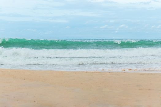 sandy beach blue sky and white formy wave