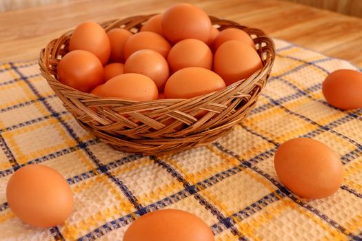 Brown chicken egg on vintage tablecloth and eggs in the basket.