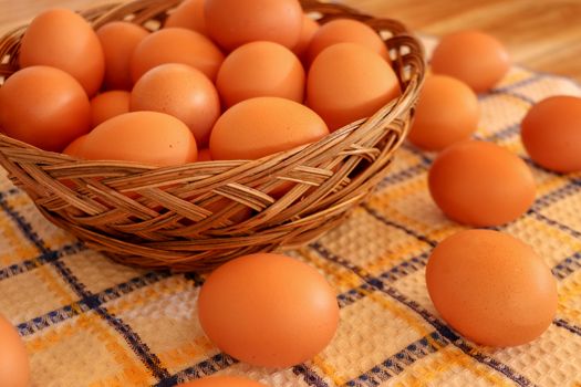 Brown chicken egg on vintage tablecloth and eggs in the basket.