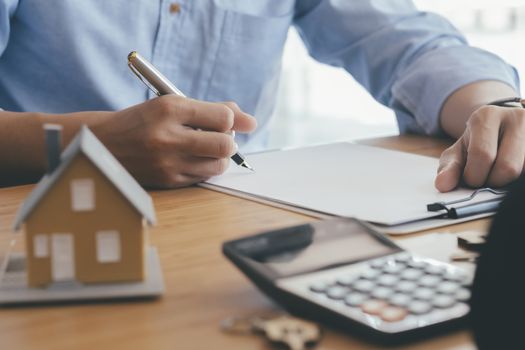 Young man is signing financial mortgage contract of sale for a new house with real estate agent at office. Business and finance real estate  buying or selling or renting house concept.