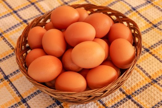 Brown chicken egg on vintage tablecloth and eggs in the basket.