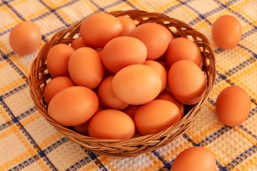 Brown chicken egg on vintage tablecloth and eggs in the basket.