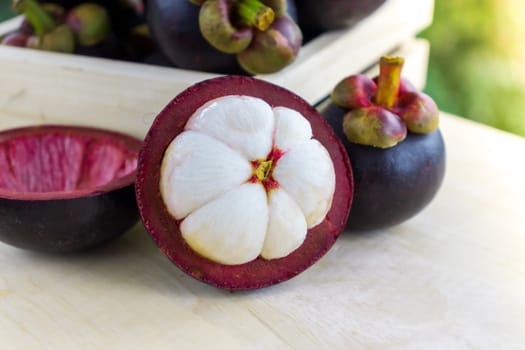 Mangosteen - The Queen of Tropical Fruit, dark-purple skin and creamy white fruit flash on wooden table