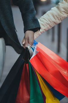 Colorful paper bags in hands of couple. Shopping and sales concept.