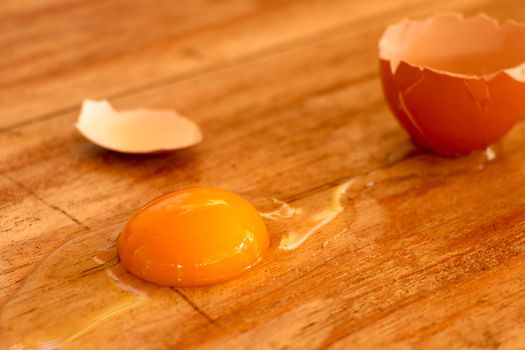 Raw broken colour egg with yellow yolk.Chicken raw, farm eggs on old wooden table.