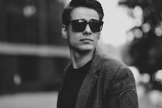 Serious stylish young man with sunglasses walking in urban street.