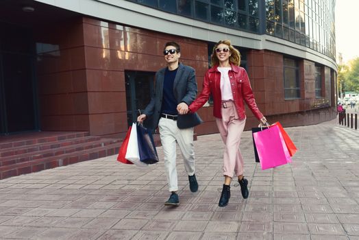 Couple in shopping together. Young couple holding hands and running through street.