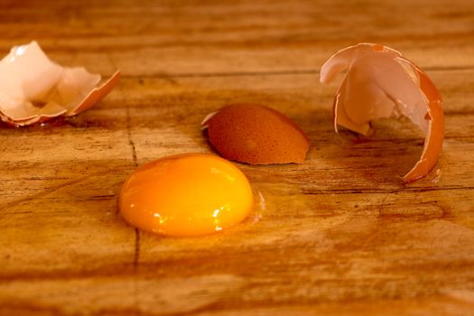 Raw broken colour egg with yellow yolk.Chicken raw, farm eggs on old wooden table.