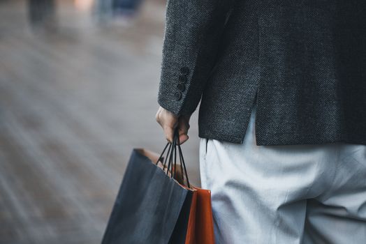 Close up of a young caucasian man holding some different paper shopping bags in the street.