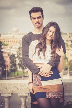 Holiday in Rome. Beautiful lovely young italian couple embracing outdoors. A couple, young man and a woman outdoors, is embracing on a terrace in the historic center of Rome, Italy.