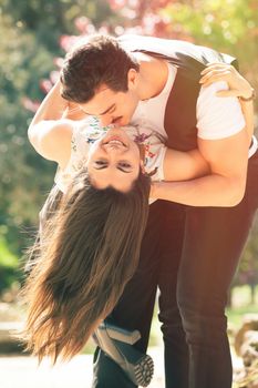 Seduction love, couple romantic relationship. Woman and man. Conquer a happy woman. A romantic man embracing and kissing a smiling woman. Outdoors with trees and flowers in the background.