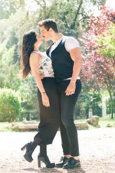 Young couple loving outdoors in a park. A young man and young woman kissing with passion and feeling. Love and falling in love.