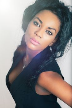 Young black woman, white background. Beautiful young African American black woman in studio on white background. Wearing a skimpy black dress. Bra in sight.