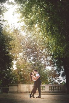 Couple in love in nature. A young couple hugging and kissing in a park under a lot of trees with green leaves. Passion and feelings