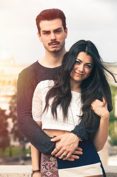 Holiday in Rome. Beautiful lovely young italian couple embracing outdoors. A couple, young man and a woman outdoors, is embracing on a terrace in the historic center of Rome, Italy.