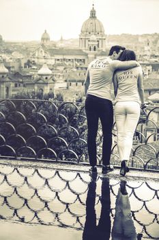 Couple hugging on holiday in Rome, Italy. Reflection in puddle. Roman view of the Pincio terrace. T-shirt with lettering King and Queen.