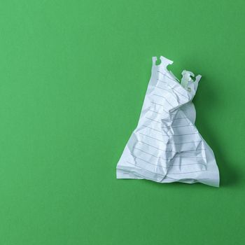 wrinkled white sheet torn from a notepad on a green background, empty space on the left