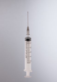 one medical syringe in an upright position on a light background