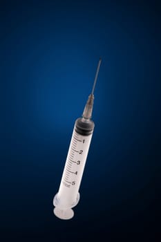 one medical syringe in an upright position on a dark blue background