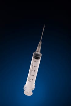 one medical syringe in an upright position on a dark blue background