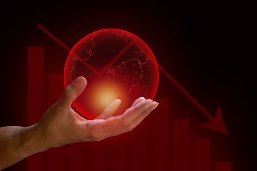 Global financial crisis concept. Human hand hold transparent red earth with graph drop arrow down on red and dark background. 